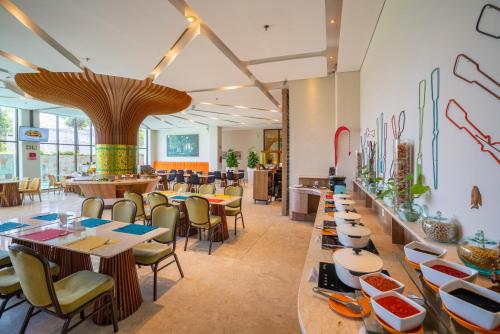 a restaurant with tables and chairs and a cafeteria at Grand Livio Kuta Hotel in Legian