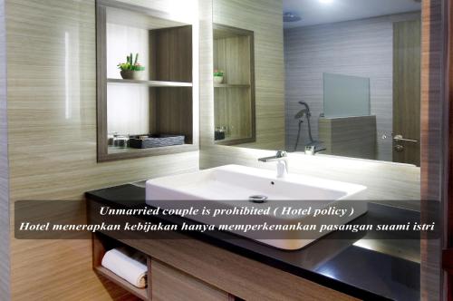 a bathroom with a white sink and a mirror at Hotel Gren Alia Cikini in Jakarta