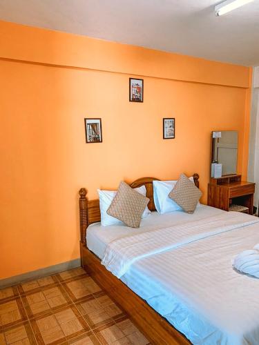 een slaapkamer met een bed met een oranje muur bij ปลื้มจิต อพาร์ทเม้น in Nonthaburi