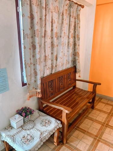 um banco de madeira num quarto com uma cortina em ปลื้มจิต อพาร์ทเม้น em Nonthaburi