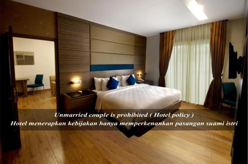 a hotel room with a bed and a desk at Hotel Gren Alia Cikini in Jakarta