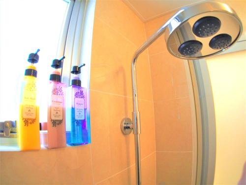 a shower with four shampoo bottles on a wall at Terrace Garden Okinawa in Yamada