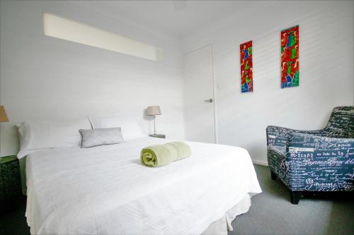 a bedroom with a white bed and a chair at Pandanus Holiday Home in Coolum Beach