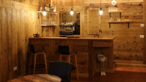 a kitchen with wooden walls and a bar with stools at Dada Mountain Hotel in Morgex