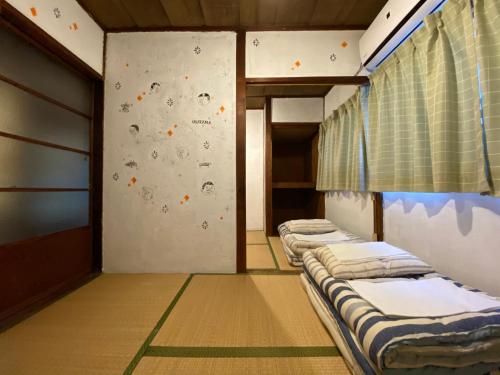 a row of beds in a room with a climbing wall at Yadokari House in Okayama