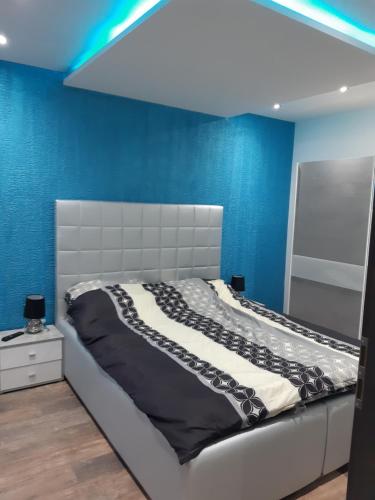 een bed in een kamer met een blauwe muur bij Dilara Apartman Sárvár in Sárvár