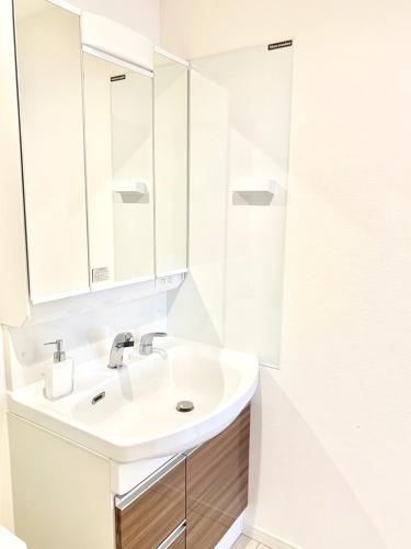 a white bathroom with a sink and a mirror at Shisa Terrace Ginoza in Ginoza