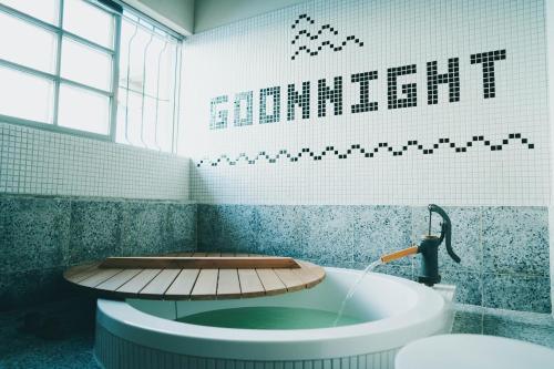 a bathroom with a bath tub with a sign on the wall at Goonnight Hostel in Kaohsiung