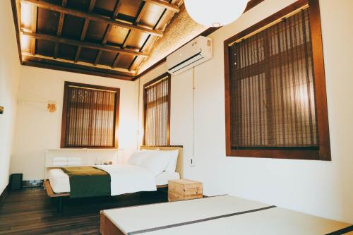a bedroom with a bed and two windows at Goonnight Hostel in Kaohsiung