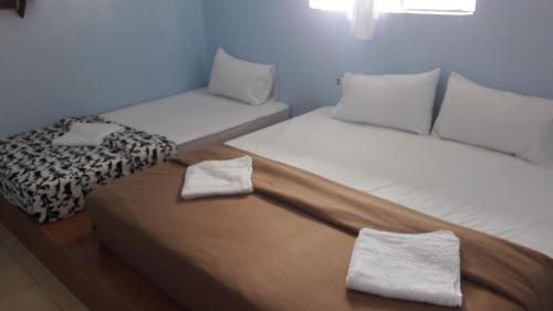 two beds in a room with towels on them at Pangkor Fish House in Pangkor