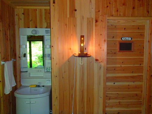 La salle de bains est pourvue de toilettes et d'un lavabo dans un mur en bois. dans l'établissement 屋久島コテージ対流山荘, à Yakushima