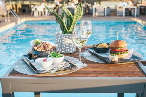 a table with food and wine next to a swimming pool at Divani Caravel in Athens