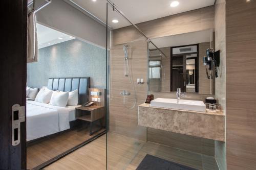 a bathroom with a bed and a sink and a shower at The Alana Hotel & Convention Center Solo by ASTON in Solo