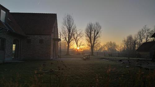 a church yard with a sunset in the background at Muntershof in Velzeke-Ruddershove