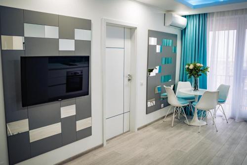 オラデアにあるTurcoazLux apartmentsのテーブルと壁掛けテレビのあるダイニングルーム