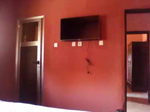 a room with a red wall with a tv on it at HAKABA in Conakry