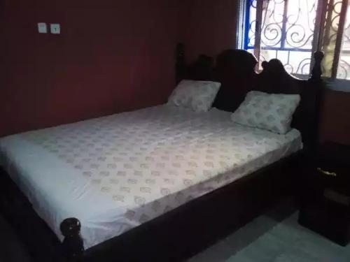 a bed with white sheets and pillows in a bedroom at HAKABA in Conakry