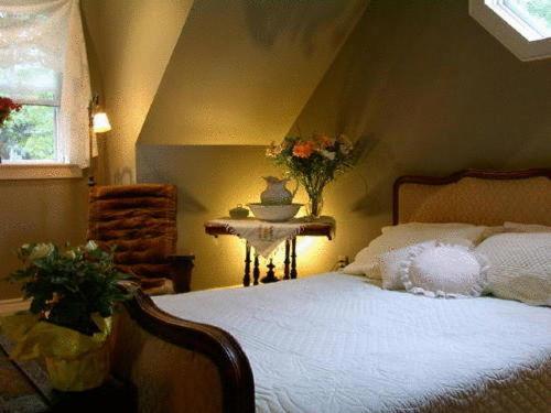 1 dormitorio con cama, mesa y ventana en Antique Slumber Old Town Bed & Breakfast, en Niagara on the Lake