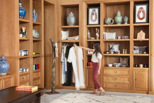 a young woman is trying on a shirt in a closet at The Oberoi Marrakech in Marrakech