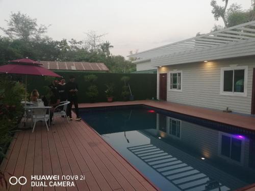 a group of people standing next to a house with a swimming pool at Supreme Hotel Yangon in Yangon