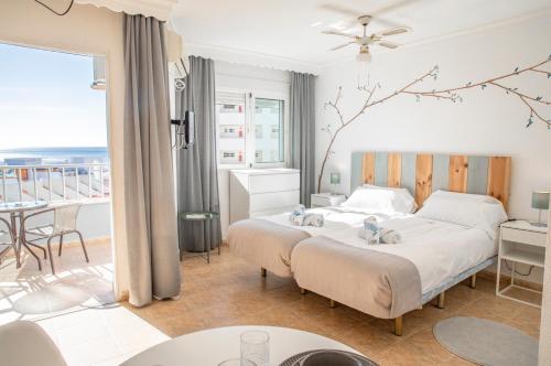 a bedroom with two beds and a balcony at Palm Beach Club Apartamentos Carihuela in Torremolinos