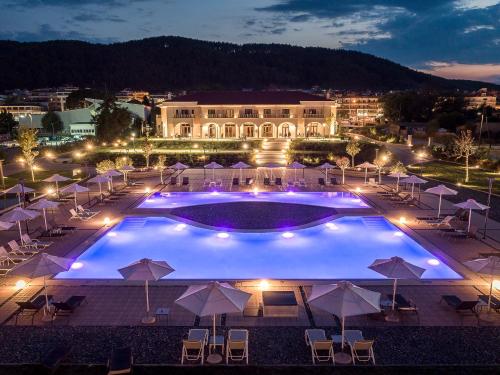 a large pool with chairs and umbrellas at night at The Lake Hotel in Ioannina