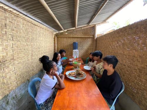 un grupo de personas sentadas alrededor de una mesa de madera en Tetebatu Terrace Homestay, en Tetebatu