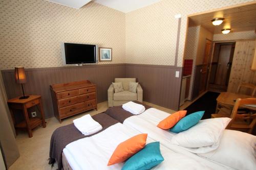a bedroom with two beds and a flat screen tv at Hotel Hullu Poro in Levi