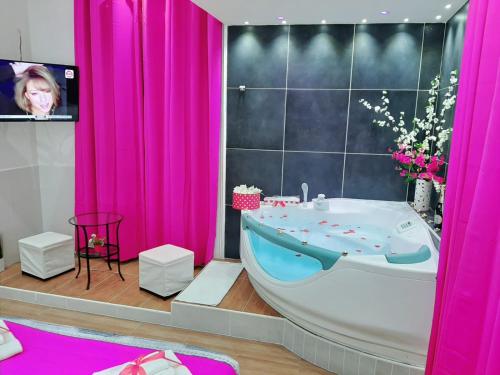 a bathroom with a tub and a tv and pink curtains at Red House in Naples