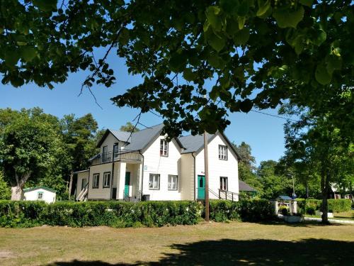 uma grande casa branca com uma árvore em primeiro plano em Gotland of Sweden - bed & breakfast em Tingstäde