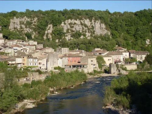 a town with a river in front of a mountain at Vogüé Meublé 2 étoiles, Un écrin de beauté et de nature in Vogüé