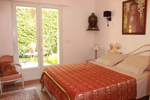um quarto com uma cama, uma cadeira e uma janela em La Villa Topi em Antibes