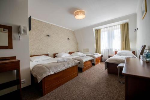 a room with four beds and a table and a window at Hotel Pałacowa in Narol