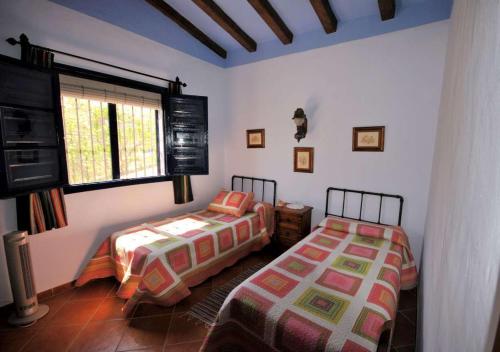 1 dormitorio con 2 camas y ventana en Villa Ruiz, en Frigiliana