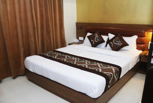 a bedroom with a large bed with brown curtains at Hotel Crystal Luxury Inn- Bandra in Mumbai