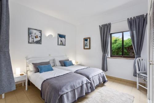 a white bedroom with a bed and a window at Prado do Golf in Vilamoura