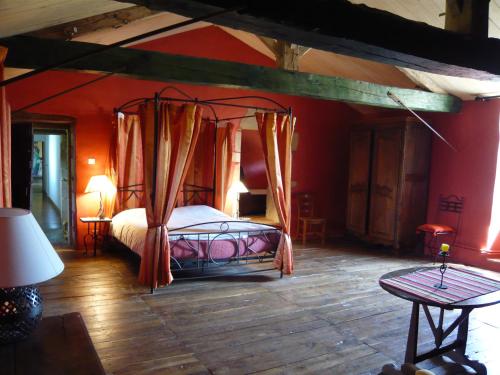 a bedroom with a canopy bed and red walls at Logis de l'Aublonnière in Sainte-Cécile