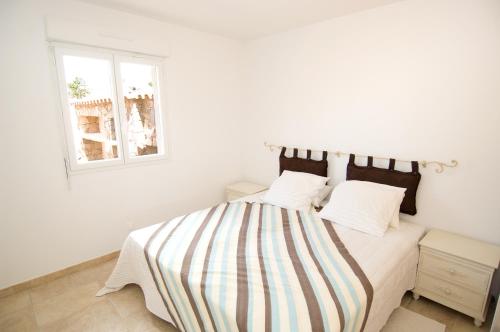 Dormitorio blanco con cama con manta a rayas en Alzitone, en Ghisonaccia