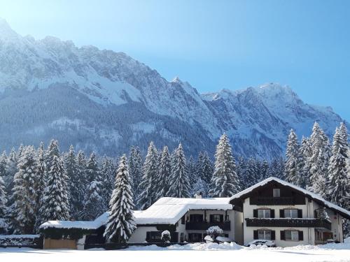 a house in the snow with mountains in the background at Gästehaus Lehnerer Grainau in Grainau