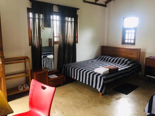 um quarto com uma cama e uma cadeira vermelha em Upland Inn em Kandy