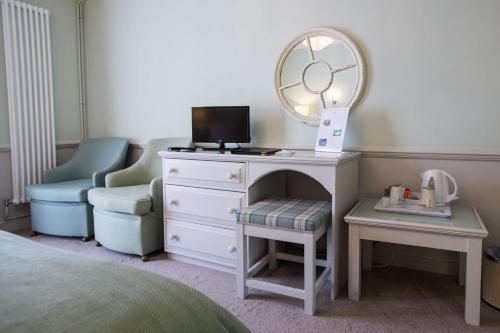 a bedroom with a dresser with a mirror and a chair at The Wyndham Hotel in Clearwell