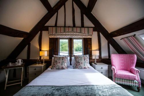 a bedroom with a bed and a chair and a window at The Wyndham Hotel in Clearwell