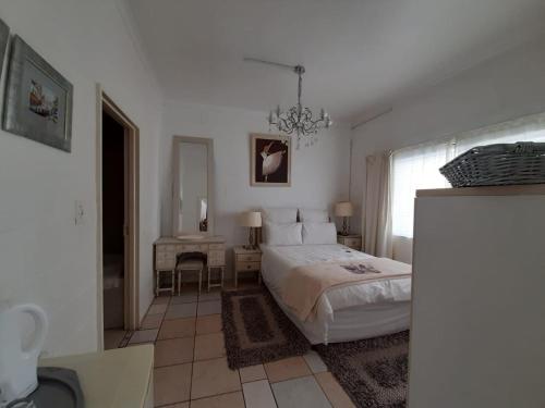 a white bedroom with a bed and a chandelier at Au Plais De Langebaan at Palm Tree Villa in Langebaan