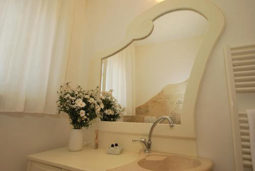 a bathroom with a sink with a mirror and flowers at Appartamento- Murex in Marina di Castagneto Carducci