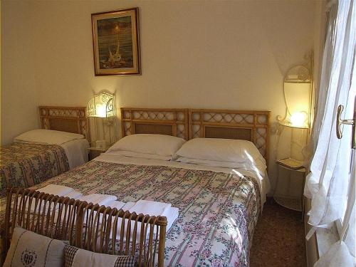 Dormitorio pequeño con 2 camas y 2 lámparas en Bougainvillea 3+3, en Marina di Castagneto Carducci
