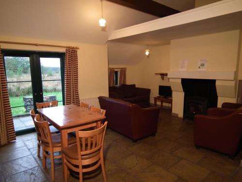 sala de estar con mesa, sillas y chimenea en An Creagán Self Catering Cottages, en Greencastle