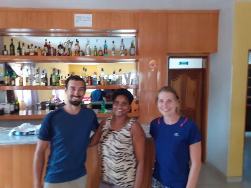 a man and two women standing in front of a bar at Dunas De Areia Preta in Ribeira da Prata