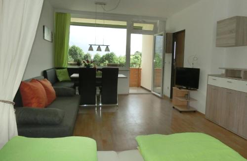 a living room with a couch and a kitchen at RUTH Haus KMB Seeblickappartement direkt am Ossiacher See mit Hallenbad Skiarena Gerlitzen in Bodensdorf