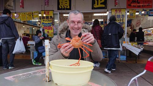 an older man holding a shrimp in a bucket at Live Cafe Hisui no Umi in Itoigawa