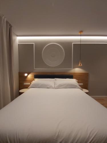 a bedroom with a large white bed with a light above it at Habital Suites in Jaca